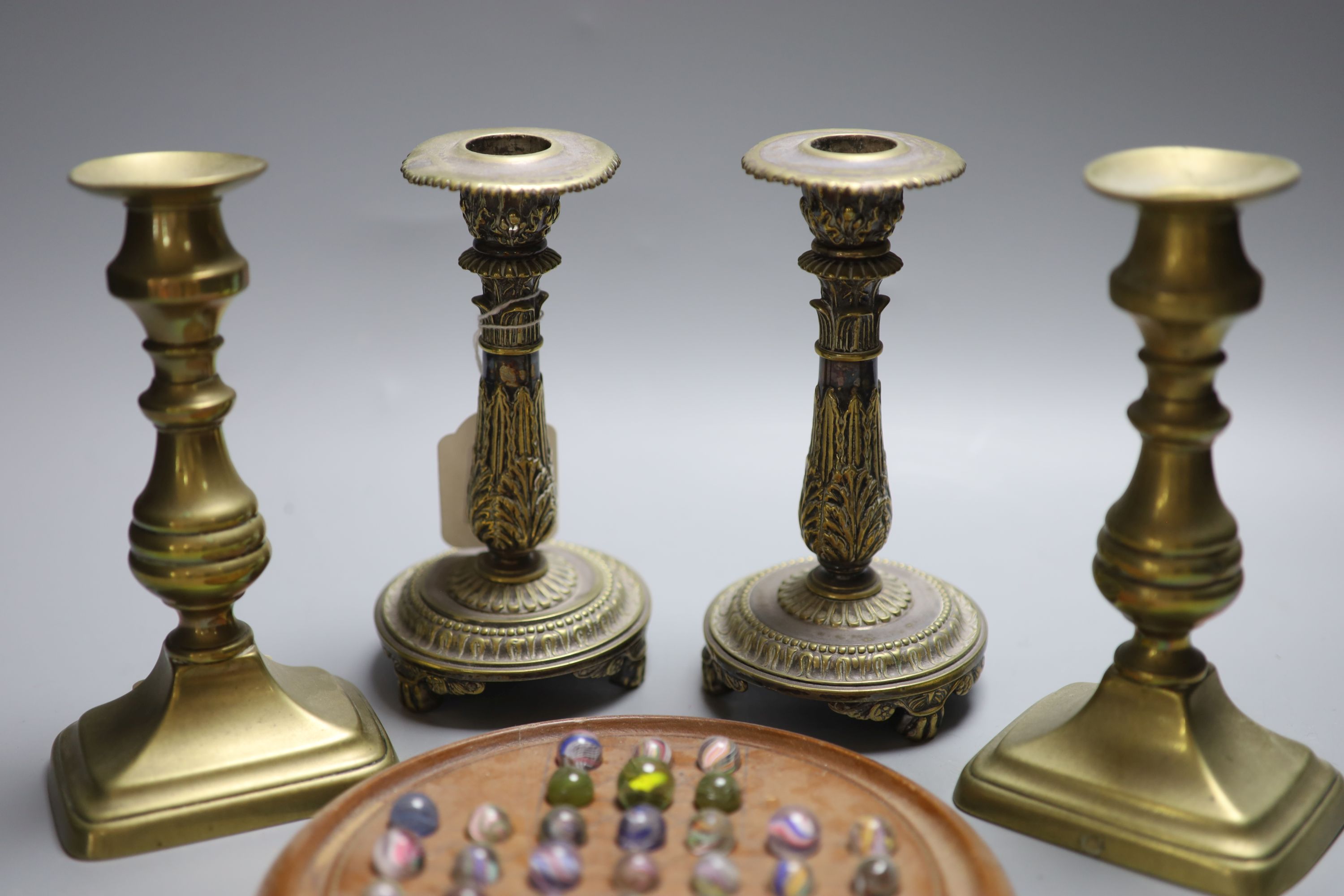 Two pairs of brass candlesticks and a solitaire board with marbles